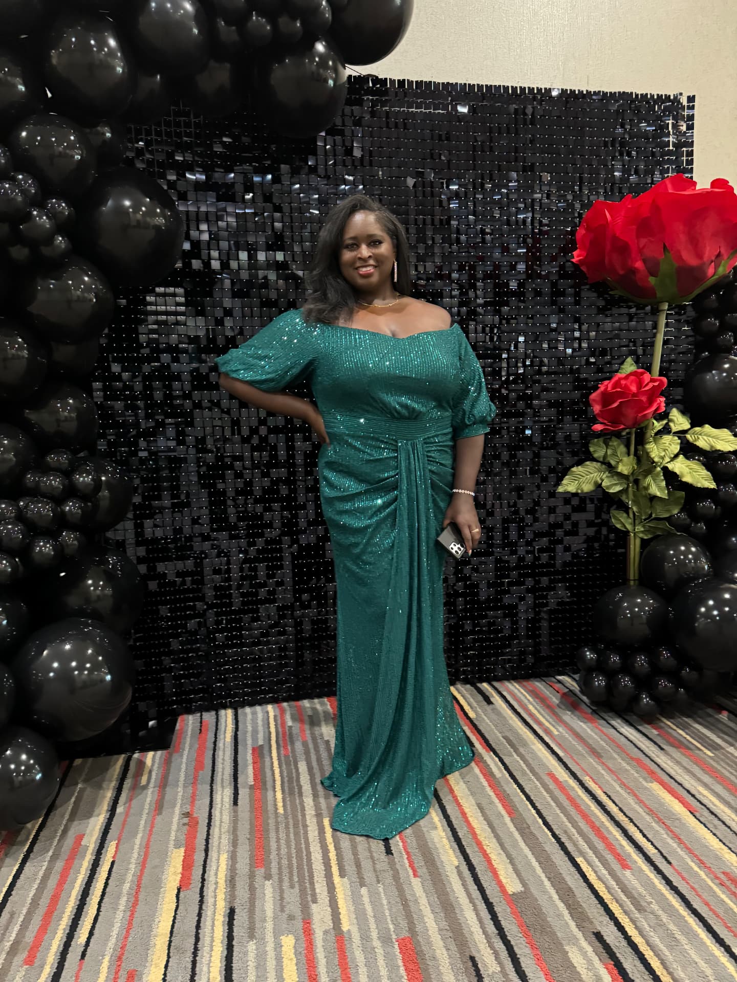 Guest in a teal gown beside oversized red roses at The Rose Ball